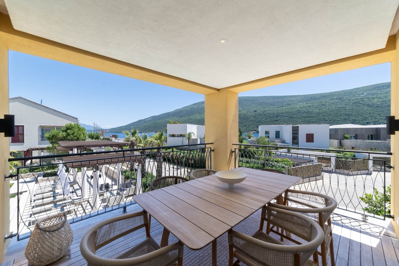 Terrace with dining area in an apartment in Portonovi, Kumbor, Montenegro: sea, mountain, and modern residential complex views.