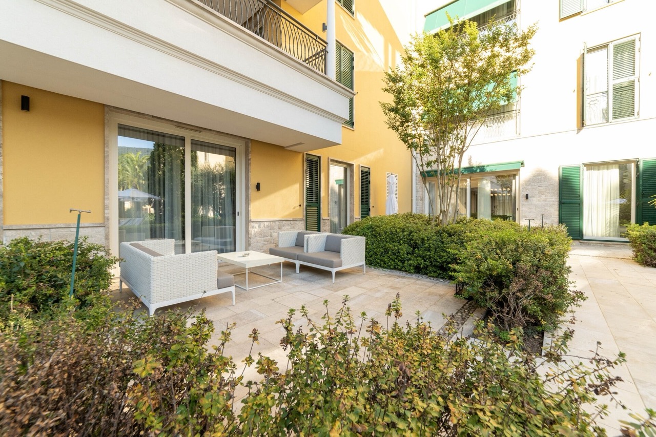Cozy terrace with wicker furniture at the apartments in Portonovi, Kumbor, Montenegro, surrounded by a green garden.