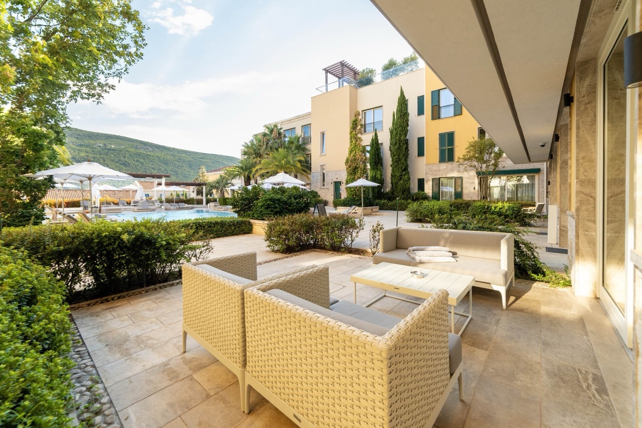 Terrace with wicker furniture and a view of the pool in the Portonovi residential complex, Kumbor, Montenegro.