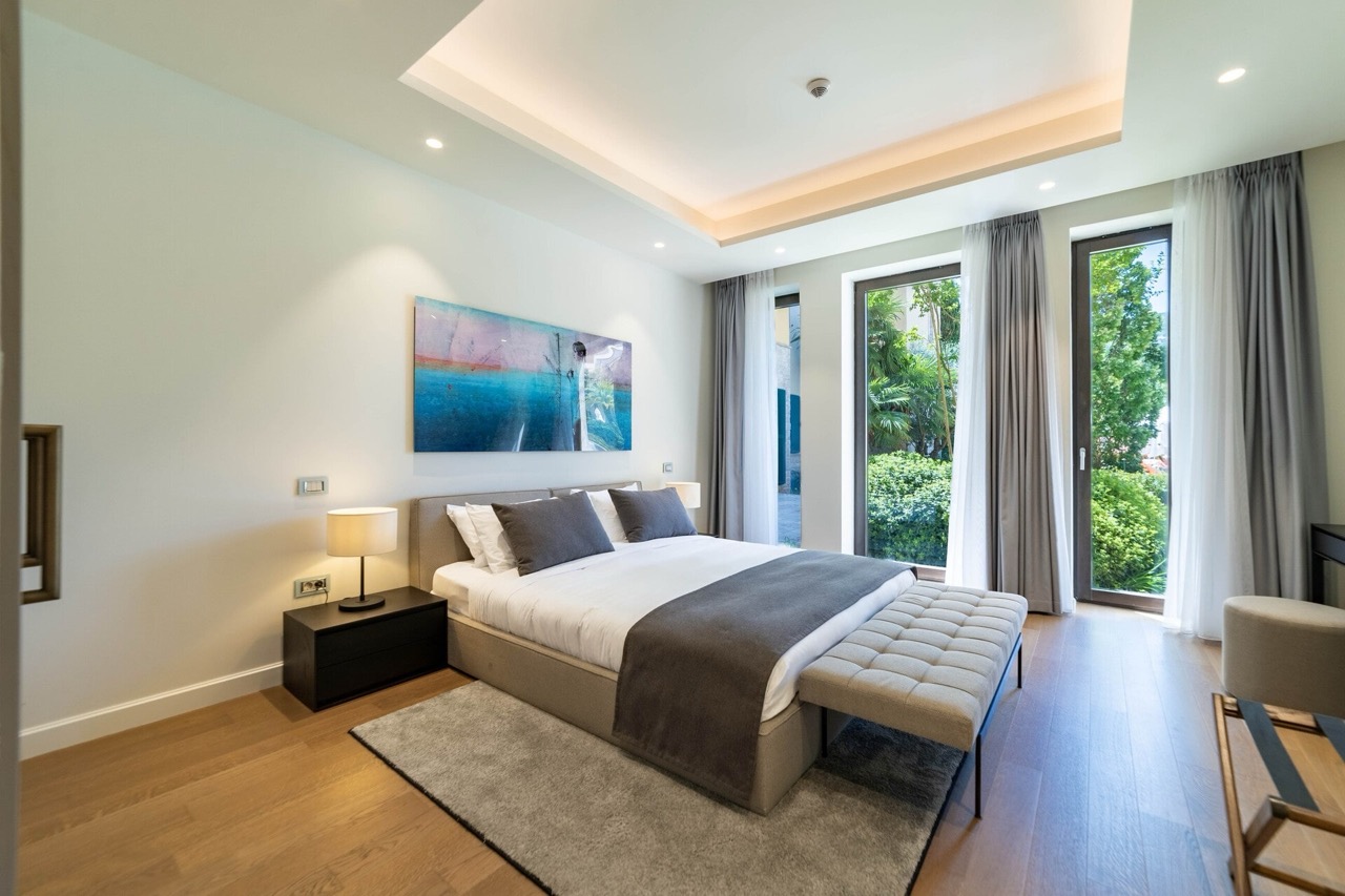 Modern bedroom in an apartment in Portonovi, Kumbor, Montenegro: double bed, panoramic windows, and garden view.