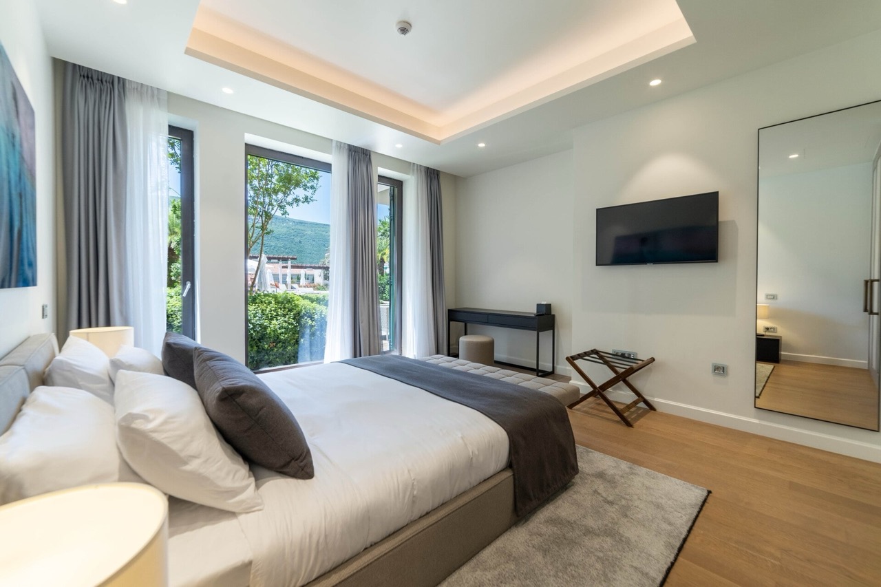 Modern bedroom in an apartment in Portonovi, Kumbor, Montenegro: double bed, panoramic windows, and garden view.