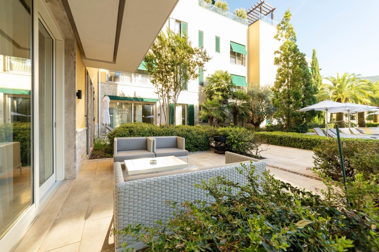 Terrace with wicker furniture in the luxury Portonovi complex, Kumbor, Montenegro: view of the landscaped garden and pool.
