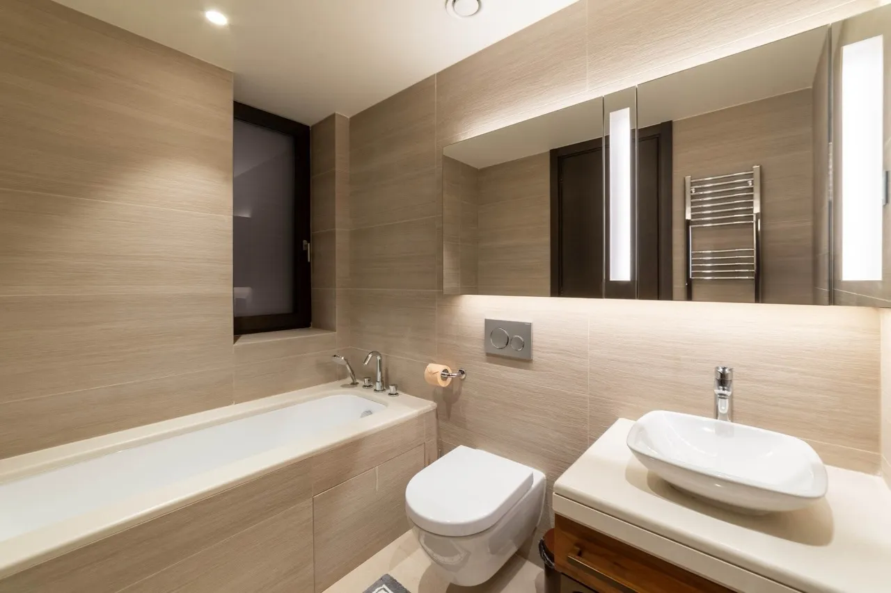 Modern bathroom featuring a white bathtub, wall-mounted toilet, and vessel sink on a vanity.
