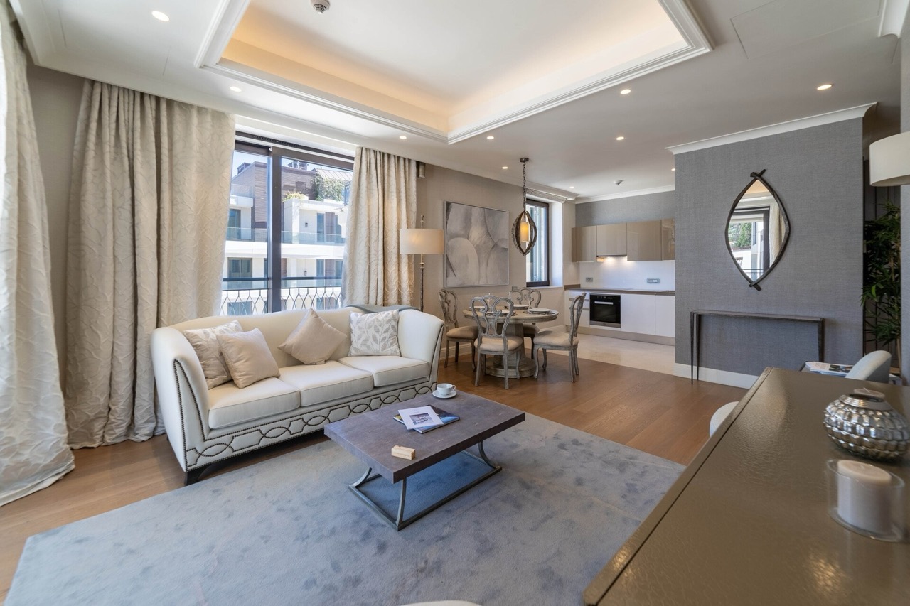 Modern living room with kitchen in an apartment in Portonovi, Kumbor, Montenegro: light furniture, parquet flooring, and panoramic windows.
