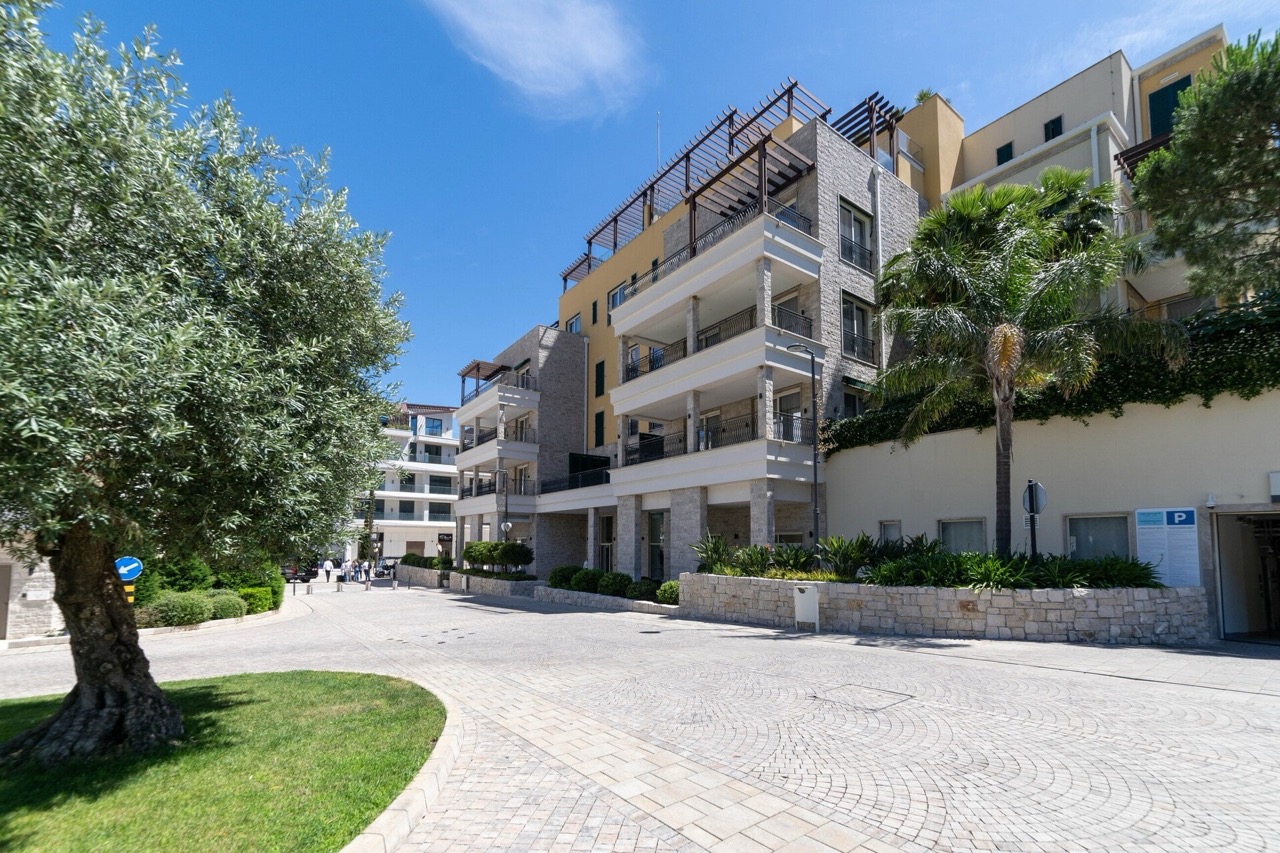 Modern residential complex in Portonovi, Kumbor, Montenegro: building facade with terraces, palm trees, and landscaped grounds