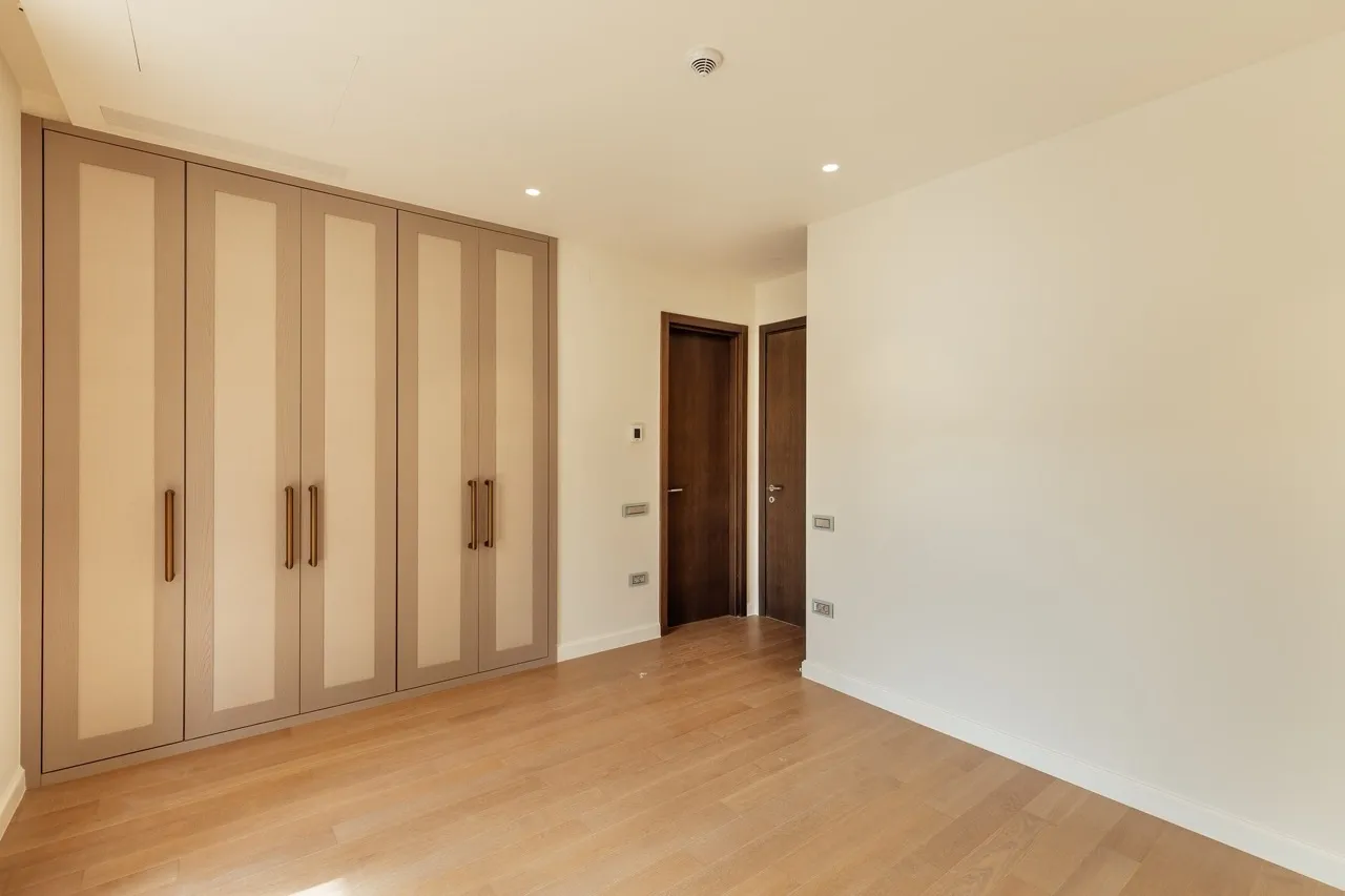Empty room featuring a large built-in wardrobe with fabric panels and light wood flooring.