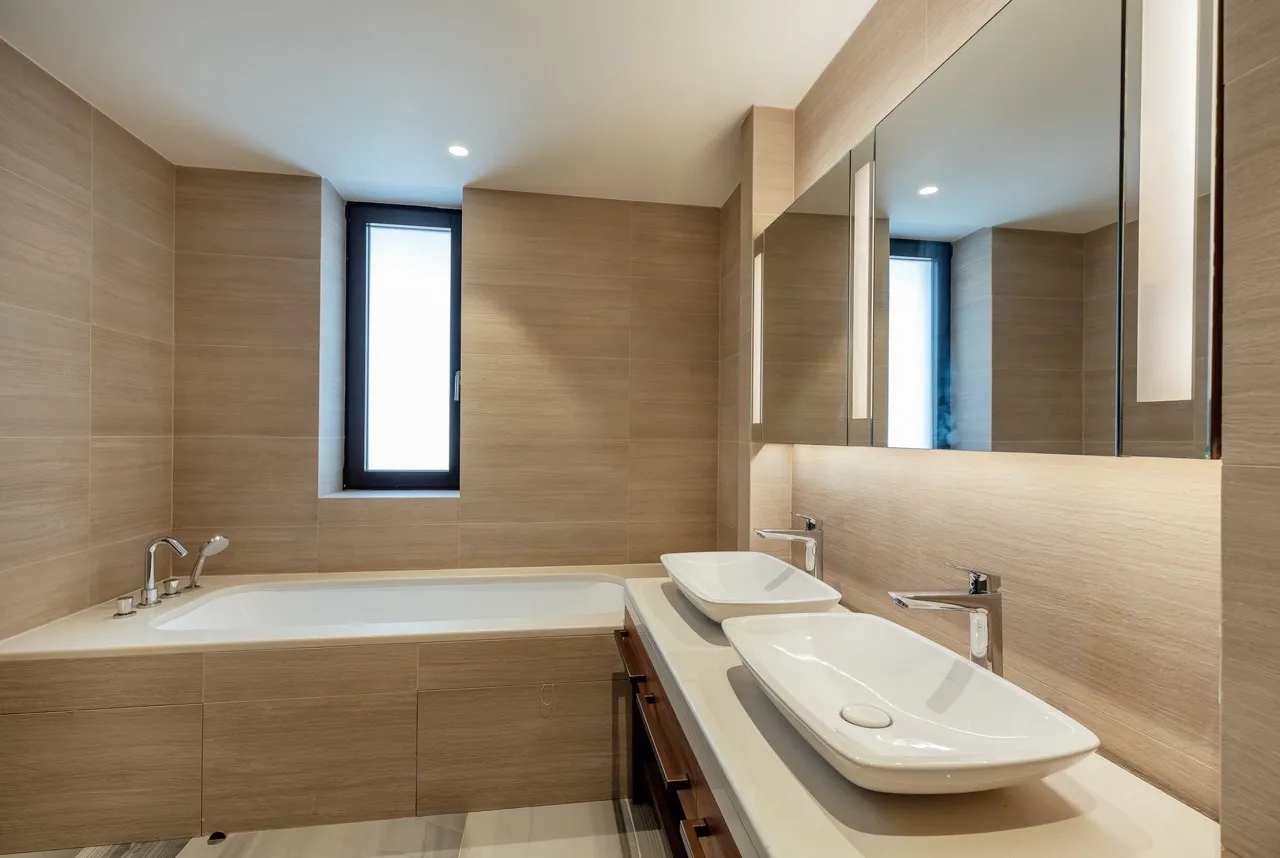 Modern bathroom featuring a large built-in bathtub and two white vessel sinks on a light countertop.
