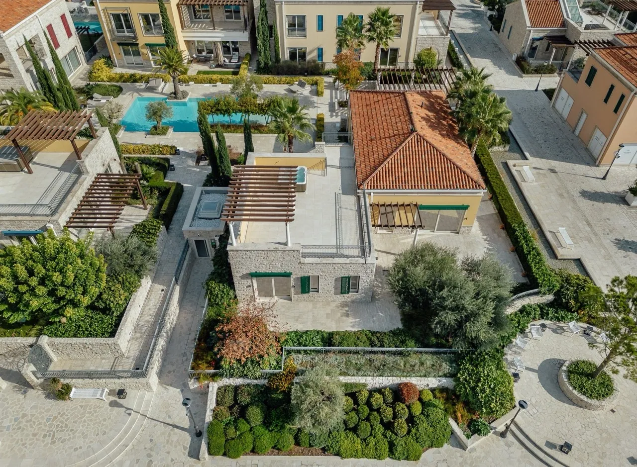 Aerial view of a villa with terracotta roof, garden, pool, and pergolas.