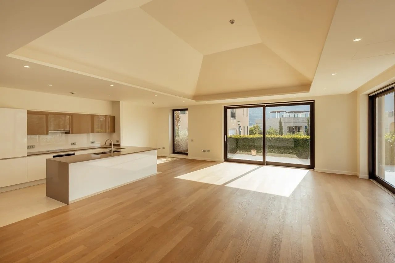 Bright open space with wood floors, kitchen island, and large sliding glass doors leading outside.