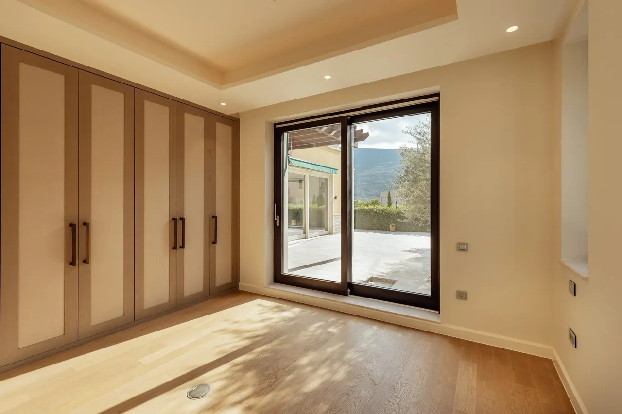 Empty room with light wood flooring and a large built-in wardrobe, featuring a sliding glass door to the terrace.