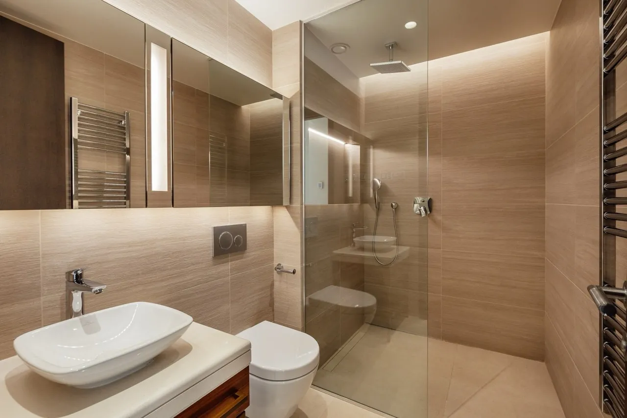 Modern bathroom featuring a vessel sink on a vanity, wall-mounted toilet, and a glass-enclosed shower area.