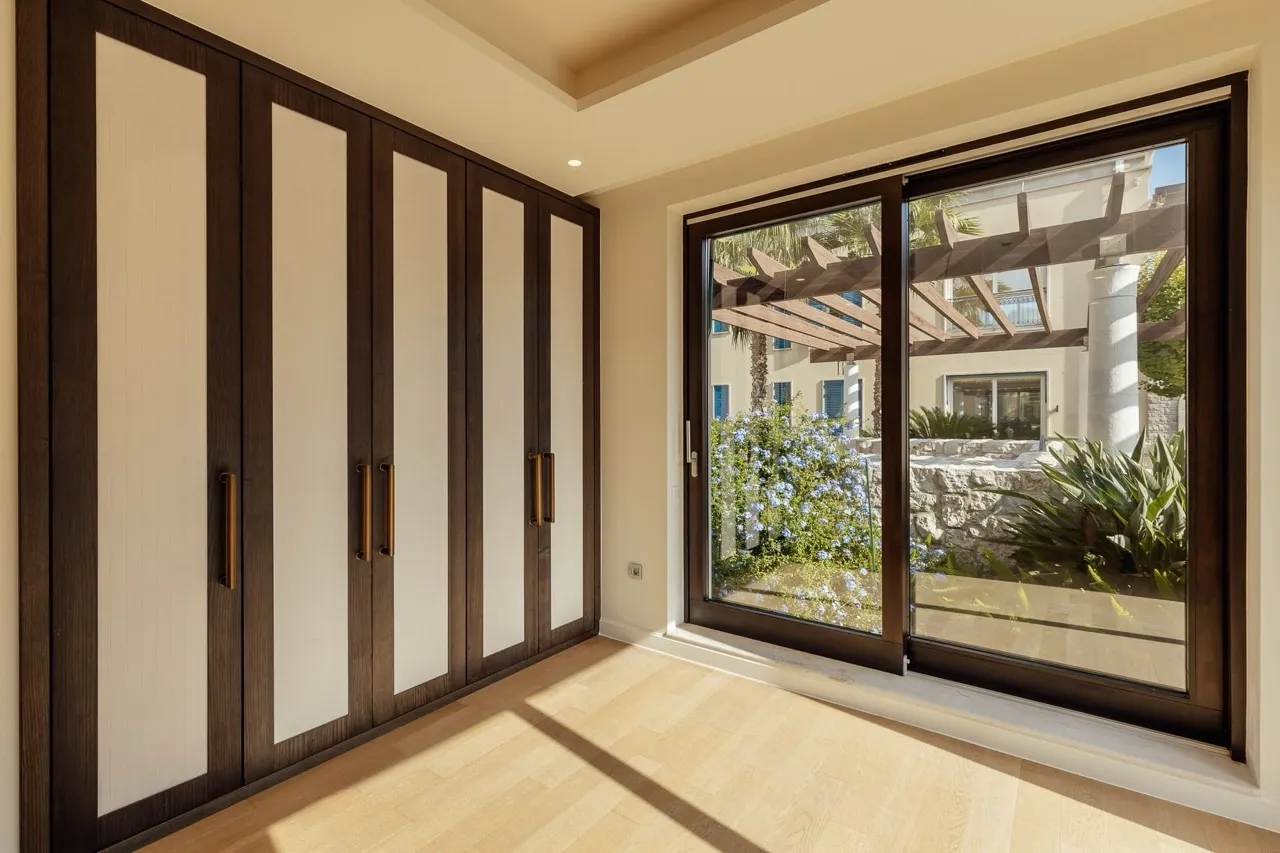 Empty room with built-in wardrobe and large glass doors opening to a garden.