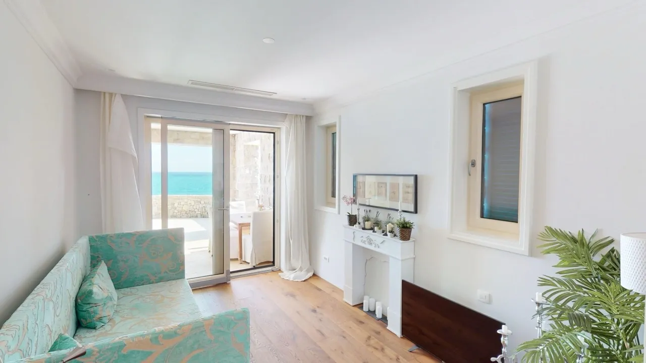 Living room with turquoise sofa, white fireplace, and sliding door leading to a sea-view balcony.