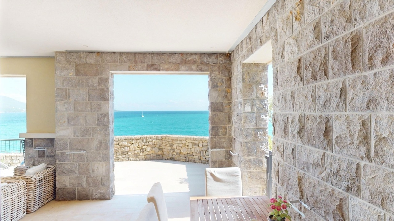 Терраса с каменной отделкой и видом на море в квартире Lustica Bay, Радовичи, Черногория.