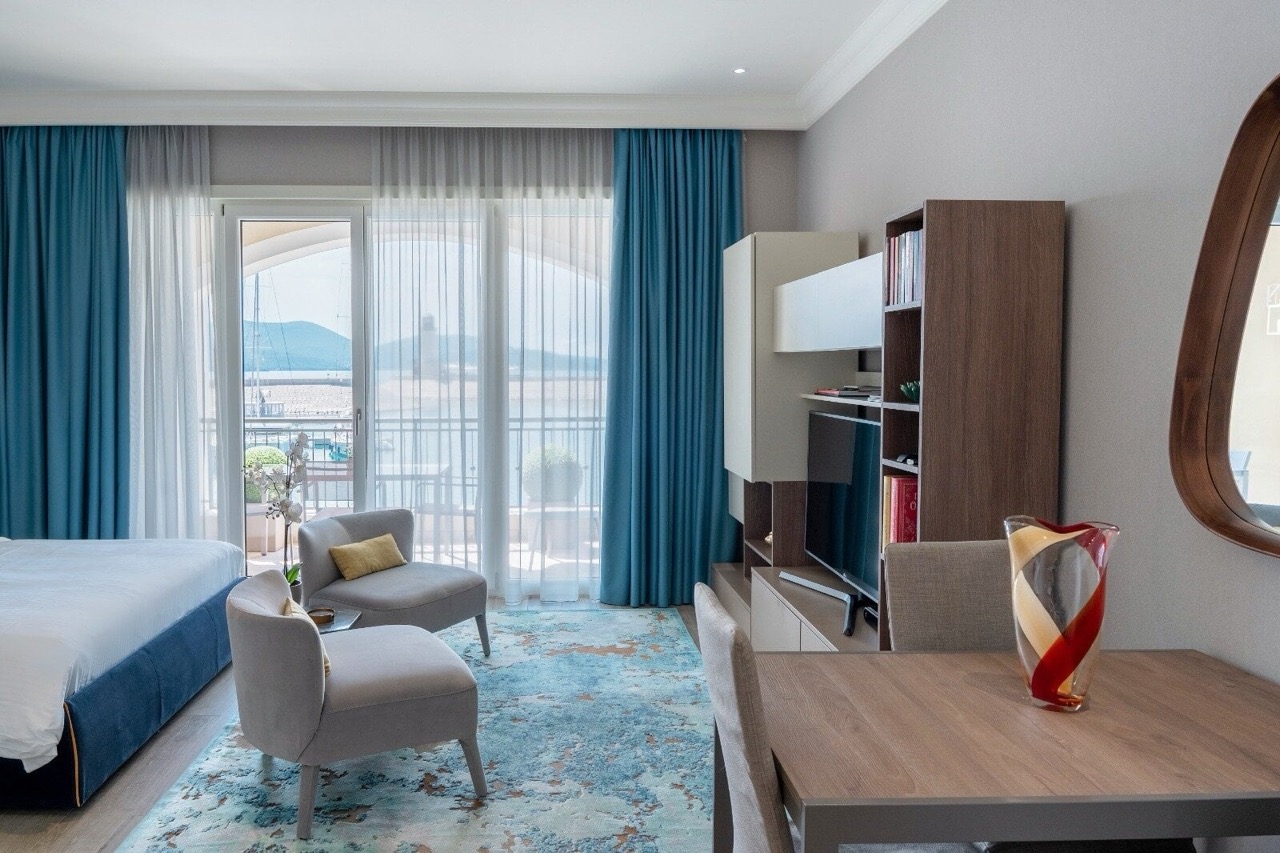 Modern living room in a Lustica Bay apartment, Radovici, Montenegro, with a view of the marina and stylish furniture.