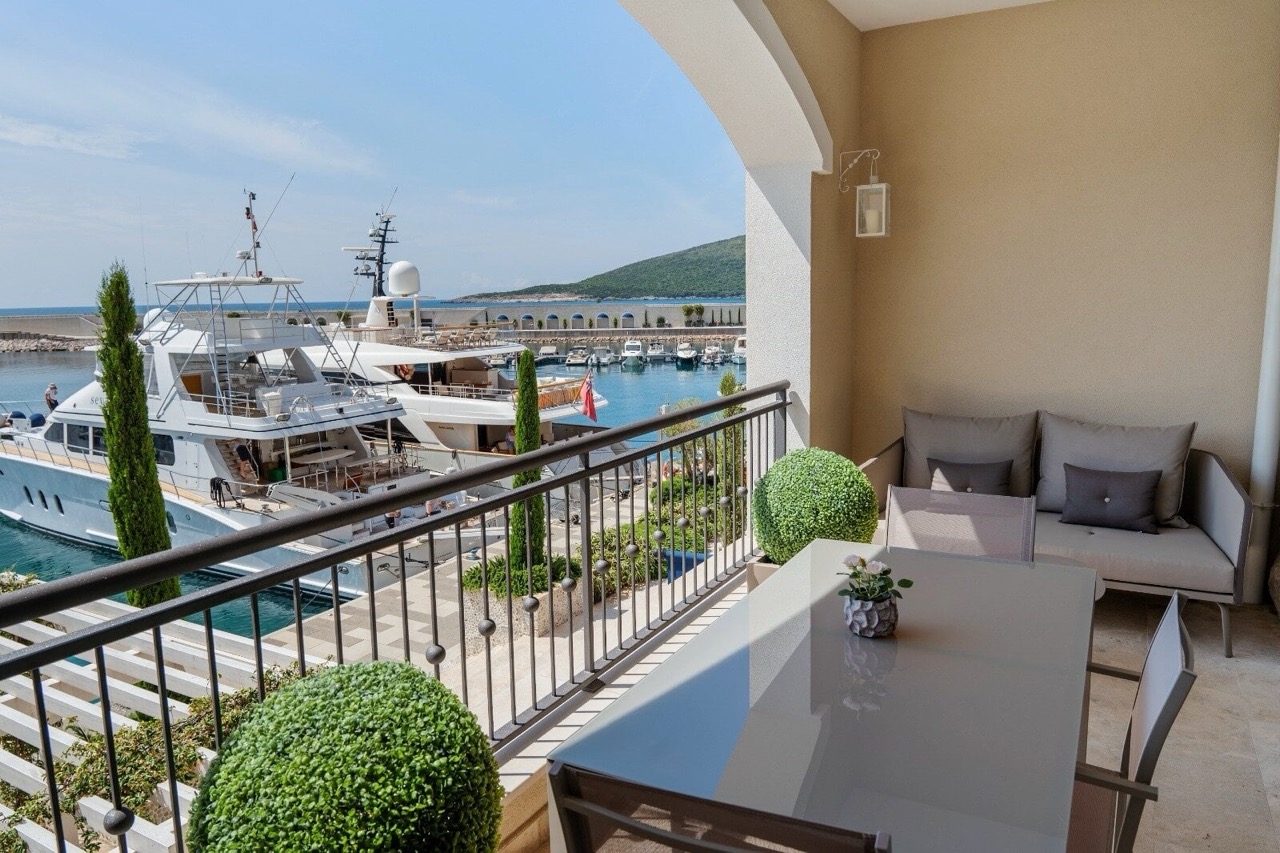Balcony with furniture and a view of the marina and yachts in Luštica Bay, Radovići, Montenegro. Luxury seaside property.