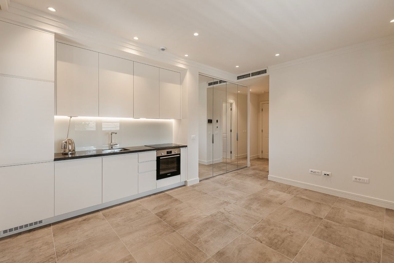 Modern kitchen in an apartment in Luštica Bay, Radovići, Montenegro: white cabinets, built-in appliances, and a mirrored cabinet.