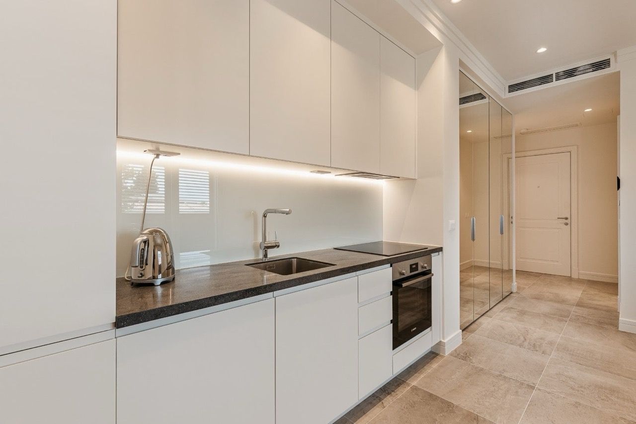 Modern white kitchen with a dark countertop in an apartment in the Luštica Bay complex, Radovići, Montenegro.