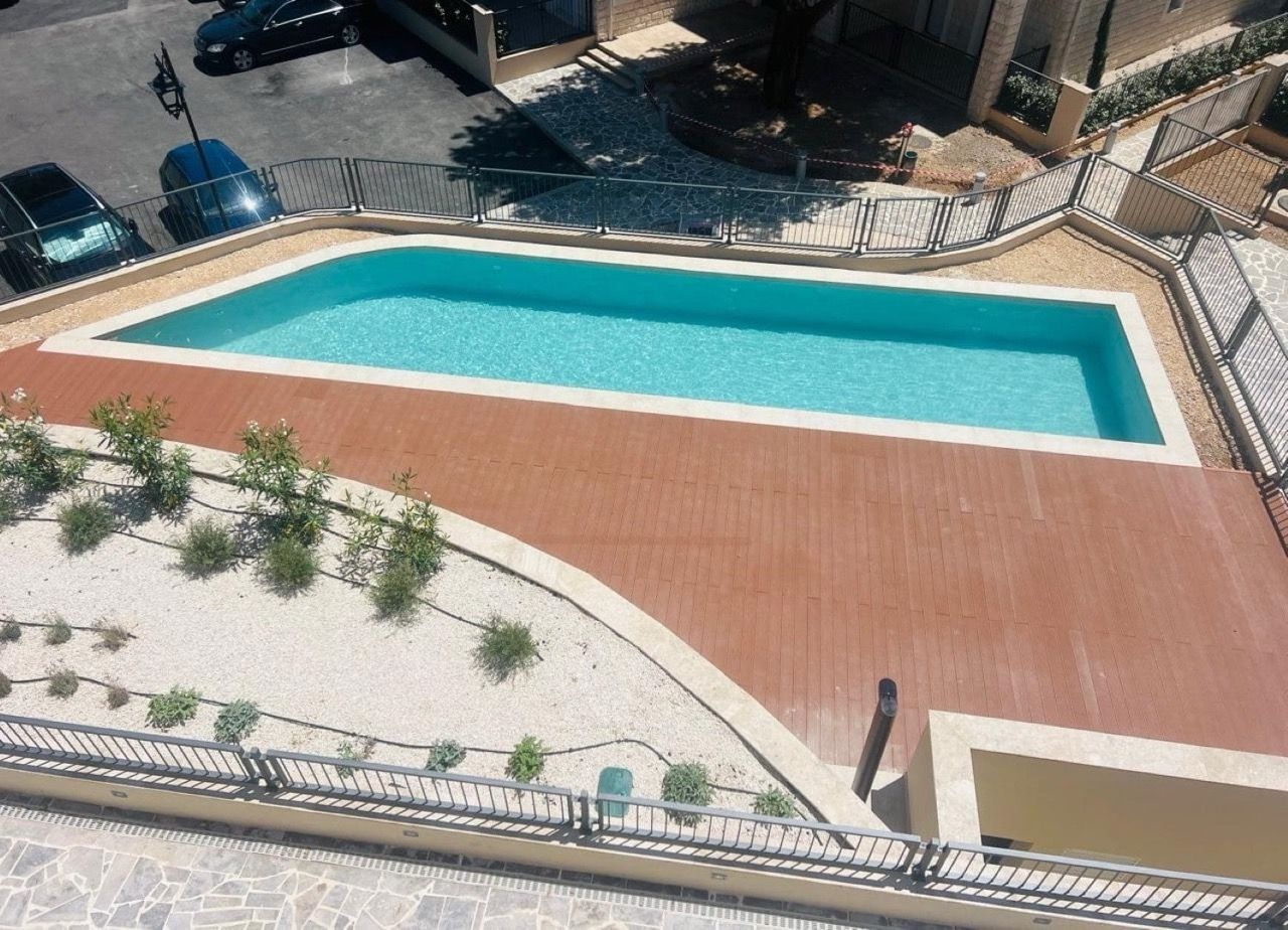 Top view of an outdoor pool with a wooden terrace in the Luštica Bay residential complex, Radovići, Montenegro.
