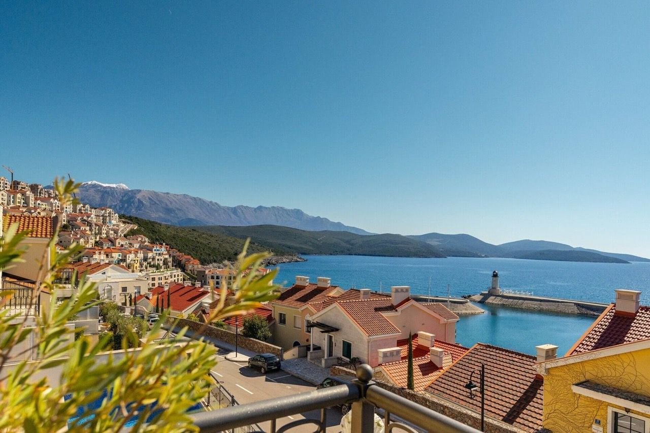 Panoramic view of the sea, the lighthouse, and Luštica Bay resort in Radovići, Montenegro, from the villa terrace with mountains in the background.