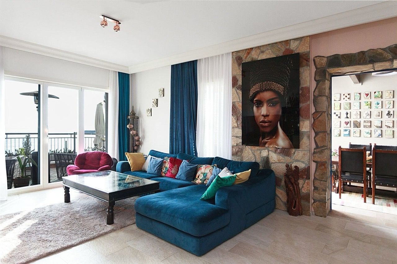 Living room with a blue sofa and stone wall in a villa in Luštica Bay, Radovići, Montenegro, with access to the terrace.