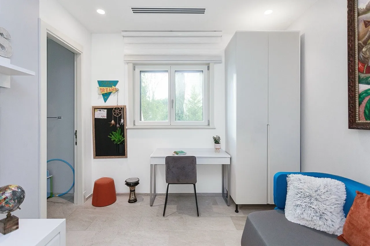Room with a desk, wardrobe, and sofa section, resembling a children's room or living area.