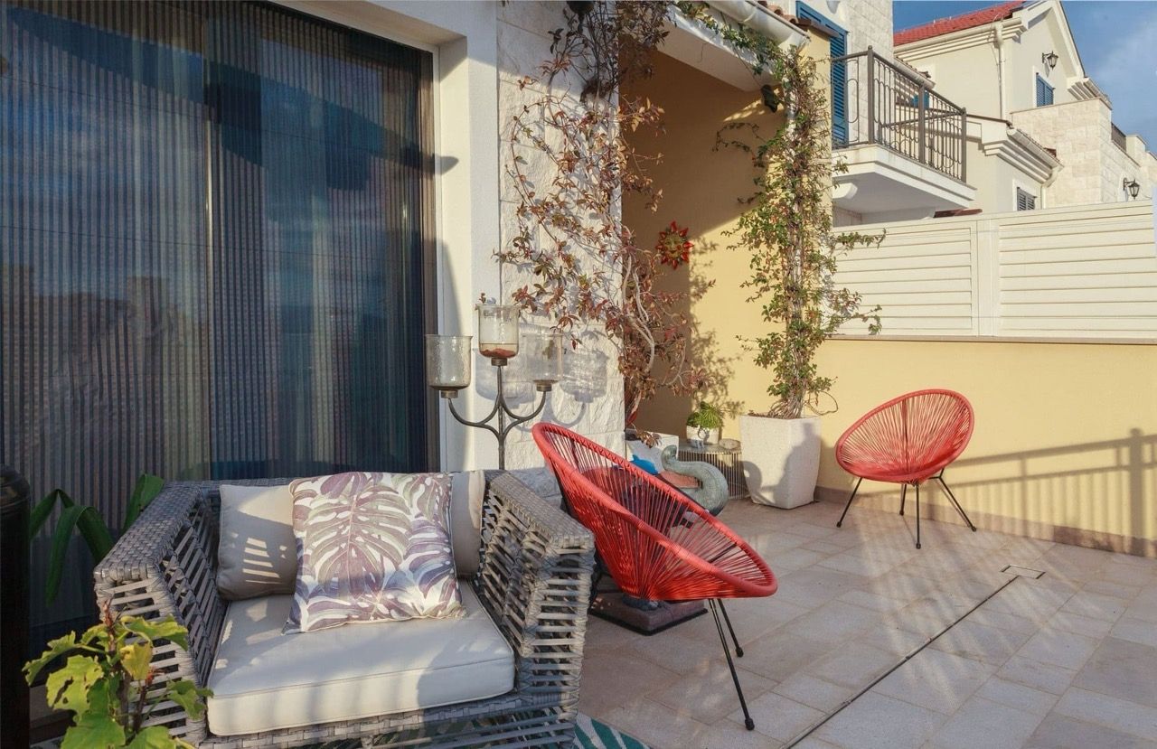 Cozy terrace with wicker furniture and red chairs at a villa in Luštica Bay, Radovići, Montenegro.
