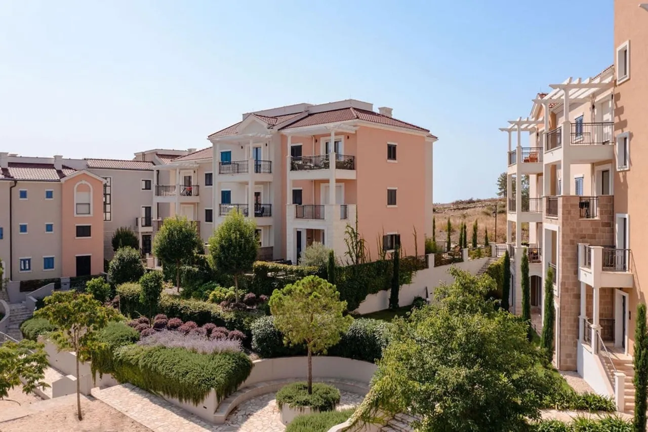 View of a residential complex with pastel multi-story buildings and a landscaped garden courtyard.