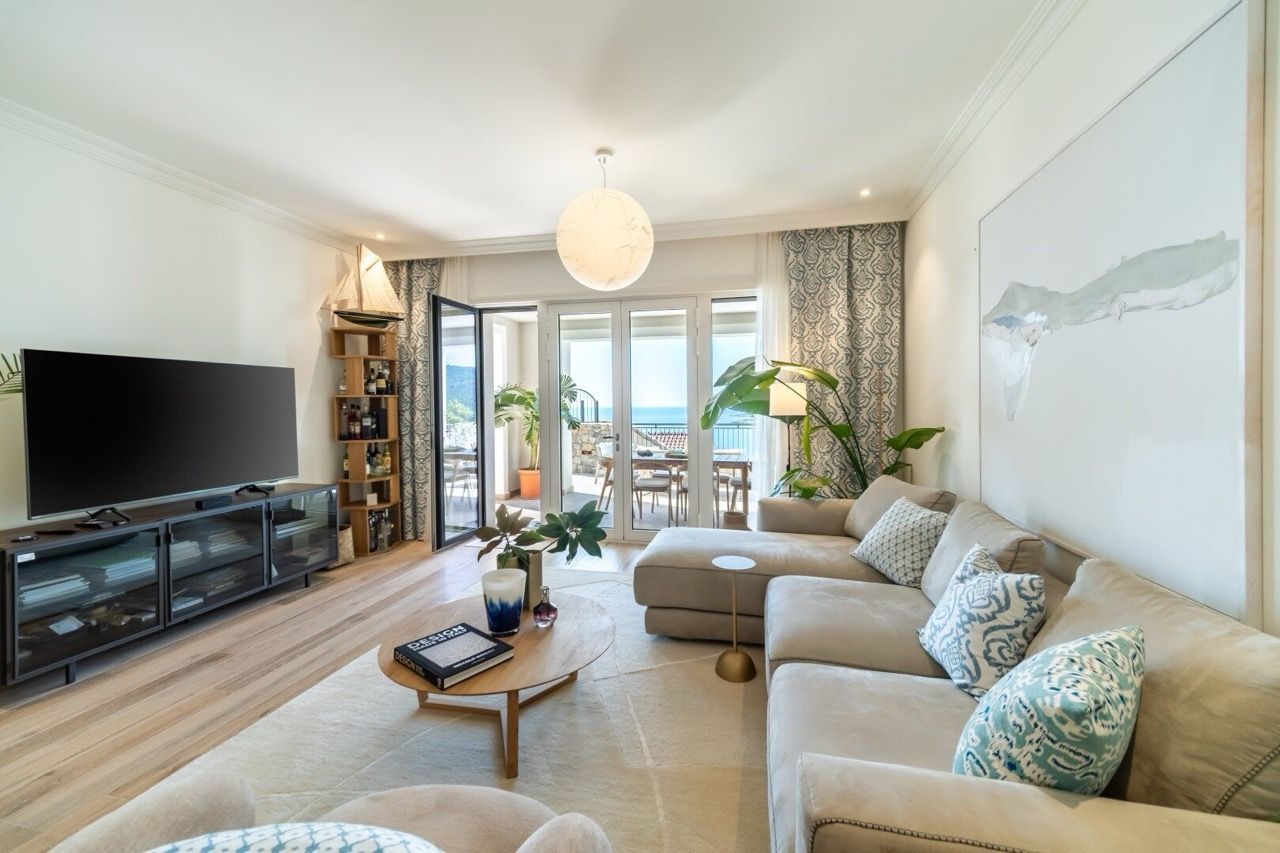 Bright living room in an apartment in Luštica Bay, Radovići, Montenegro: a soft sofa, a terrace with sea view, and stylish decor.