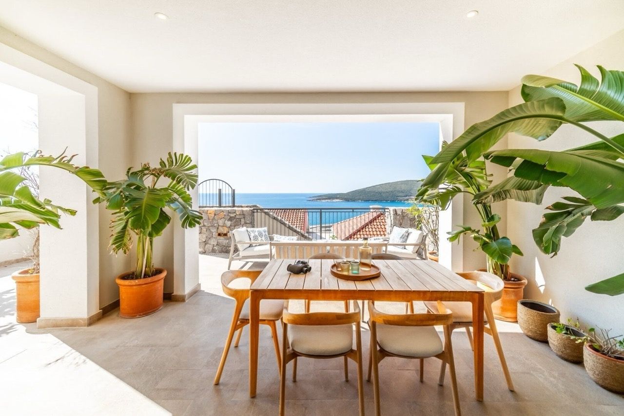 Terrace with dining area and sea view in an apartment in Luštica Bay, Radovići, Montenegro: wooden table and plants.