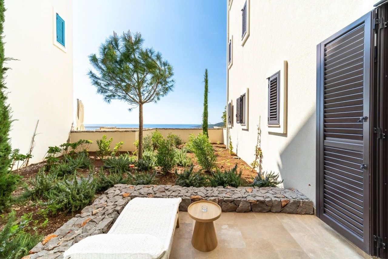 Terrace with sea view in Luštica Bay apartments, Radovići, Montenegro: sun lounger, garden, and stone finish.