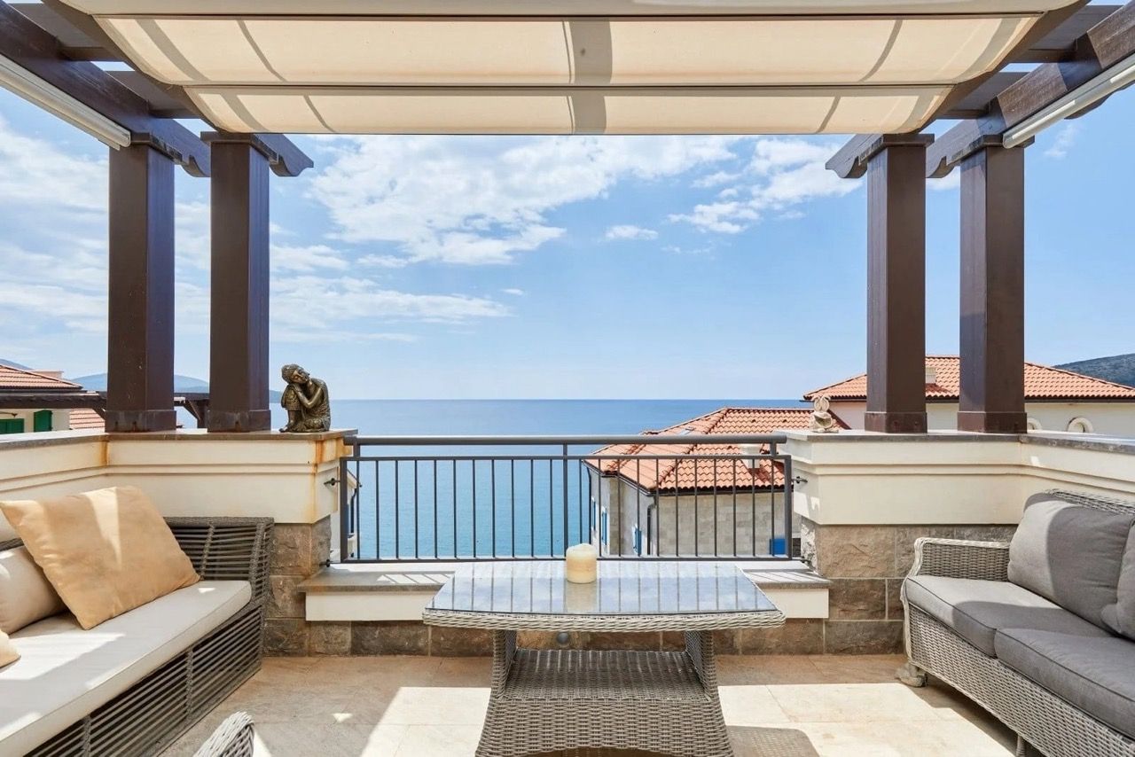 Terrace with wicker furniture and sea view in a Lustica Bay apartment, Radovici, Montenegro.