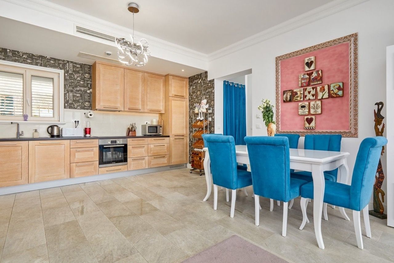 Kitchen-dining room with wooden cabinetry and blue chairs in an apartment in Luštica Bay, Radovići, Montenegro.