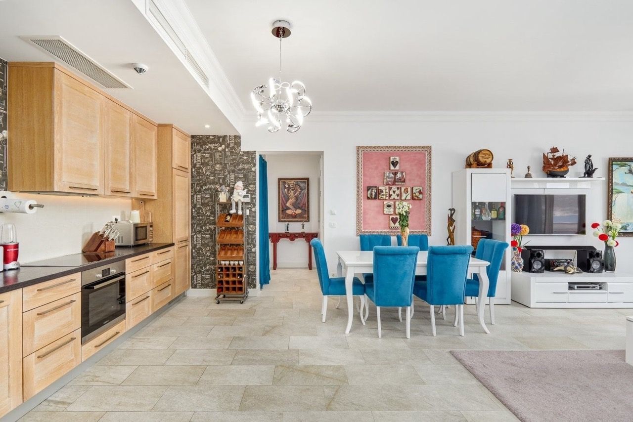 Living room with kitchen in an apartment in Luštica Bay, Radovići, Montenegro: light furniture, blue chairs, and a stylish interior.