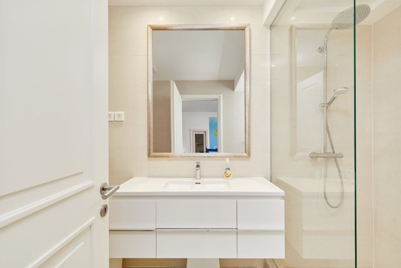 Modern bathroom with a shower cabin in an apartment in Luštica Bay, Radovići, Montenegro: white furniture and tiles.