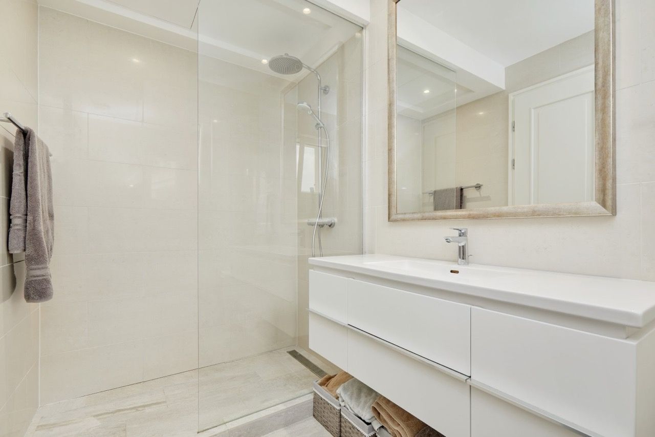 Modern bathroom with a shower cabin and white furniture in the Lustica Bay apartments, Radovici, Montenegro.