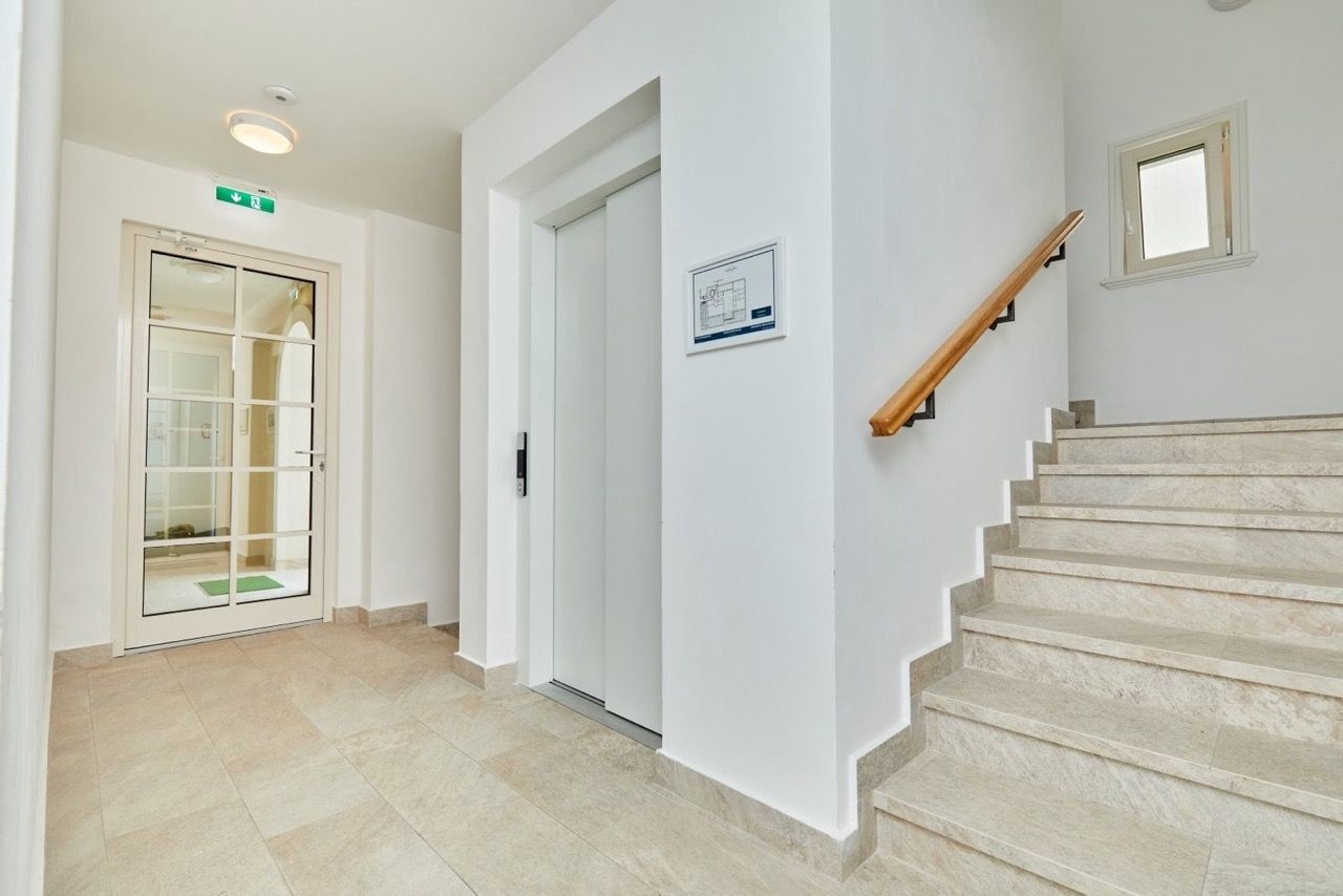 Bright entrance hall with elevator and stone staircase in the Luštica Bay residential complex, Radovići, Montenegro.