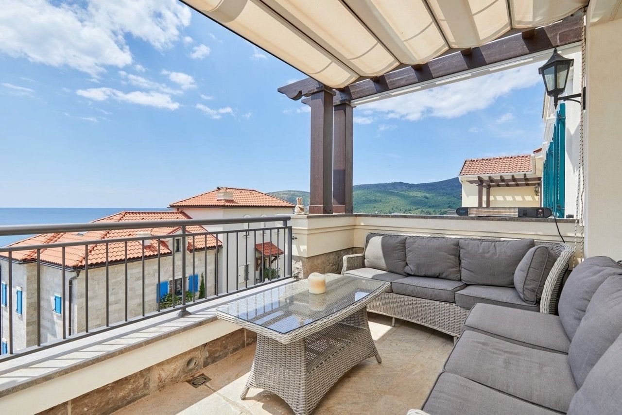 Terrace with wicker furniture and sea view in an apartment in Luštica Bay, Radovići, Montenegro.