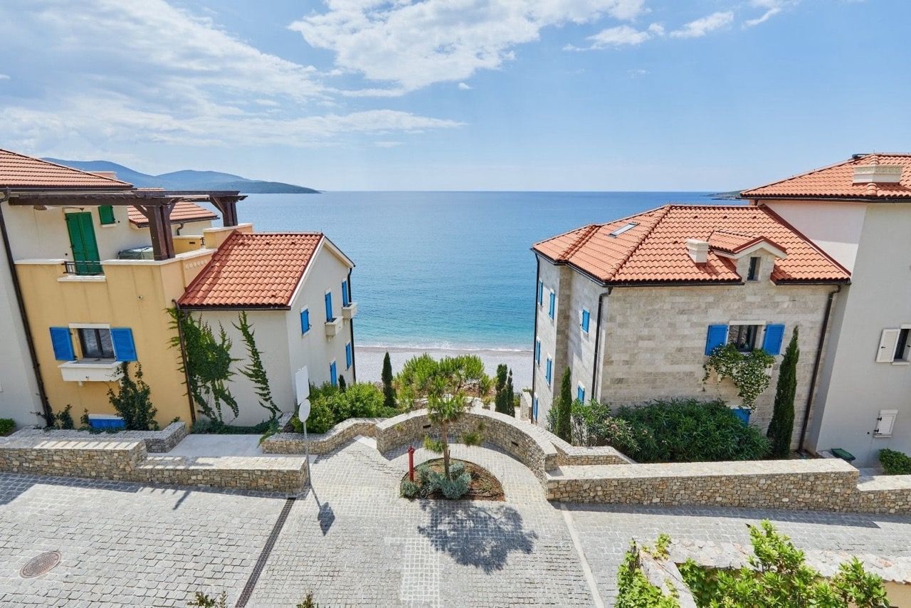 Sea and beach view from the luxury Lustica Bay complex, Radovici, Montenegro: stone villas and paved grounds.