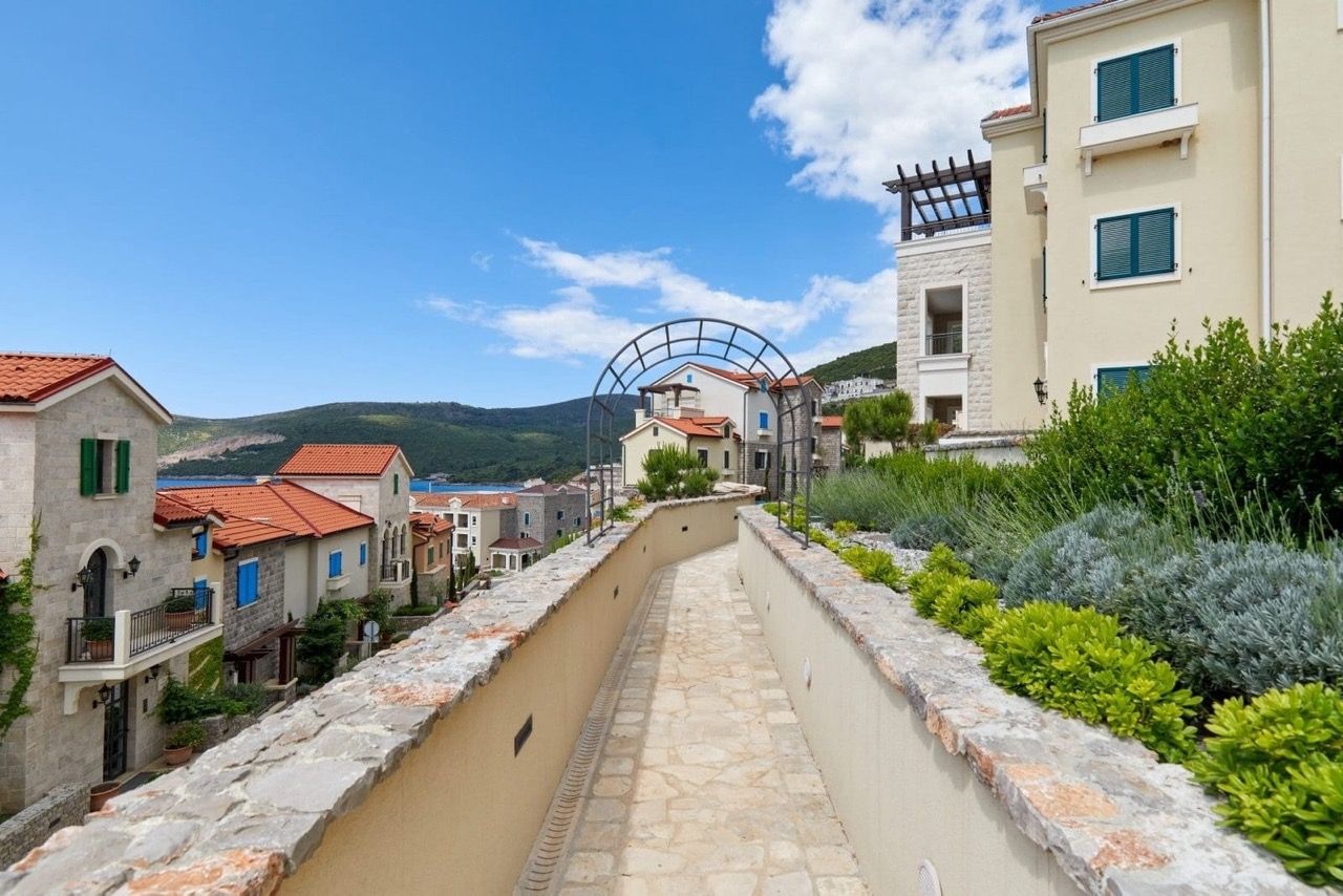 View of the Lustica Bay residential complex in Radovici, Montenegro: stone paths, landscaping, and Mediterranean villas.