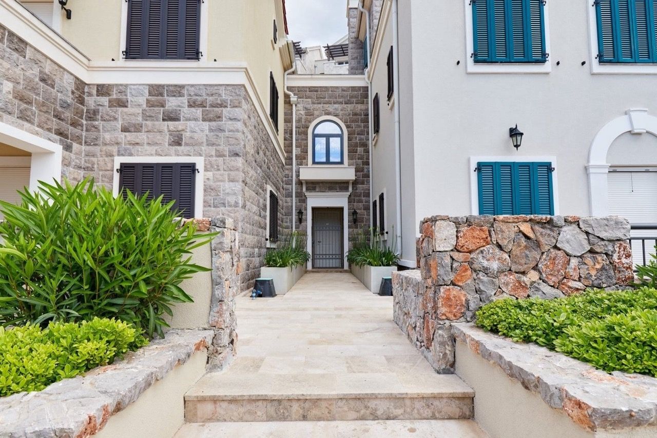 Entrance to a luxury apartment in Luštica Bay, Radovići, Montenegro: stone facade finish, terrace, and landscaping.