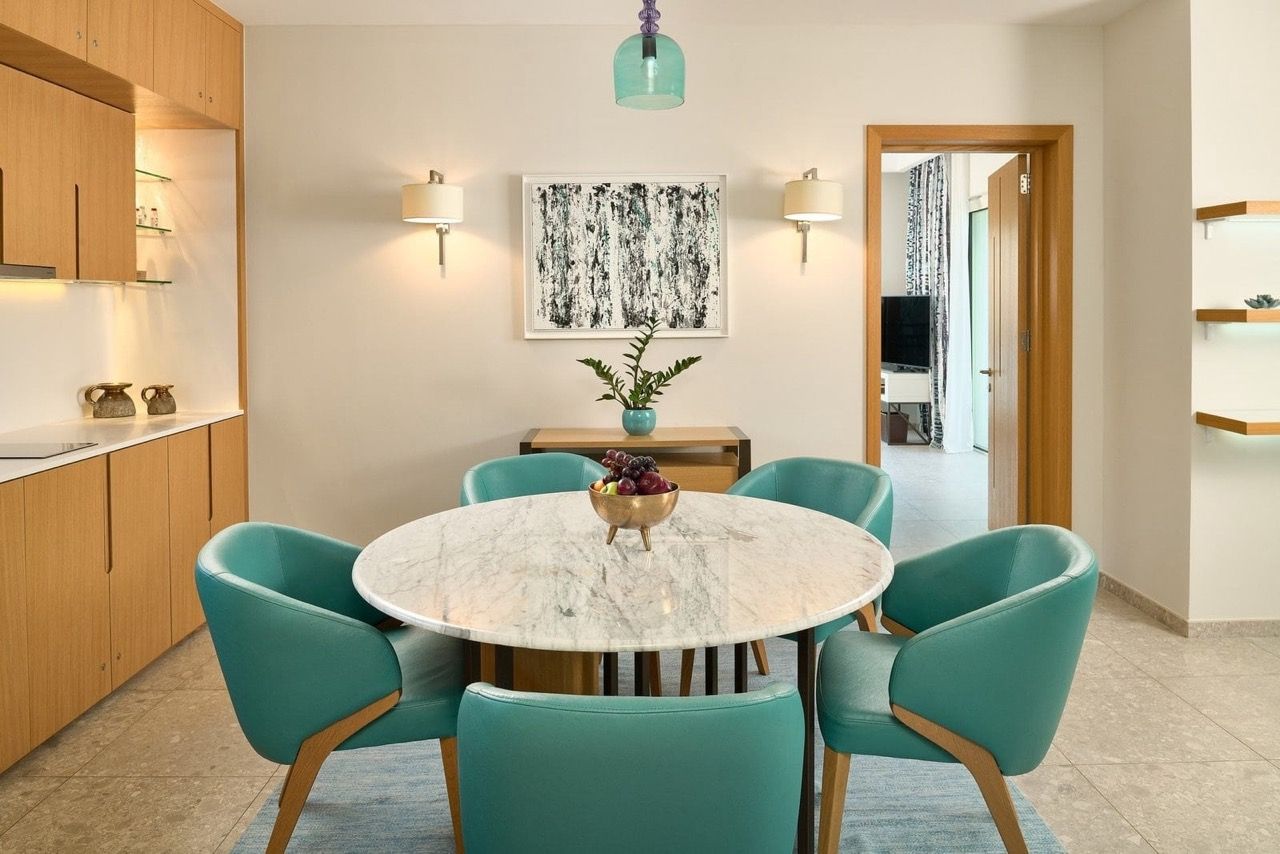 Dining area with a marble table and turquoise chairs in an apartment in Lustica Bay, Radovici, Montenegro.