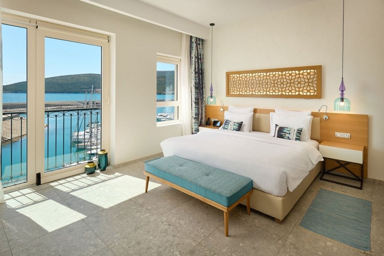 Bedroom with a view of the marina in Luštica Bay, Radovići, Montenegro: a double bed, stylish decor, and a balcony by the sea.