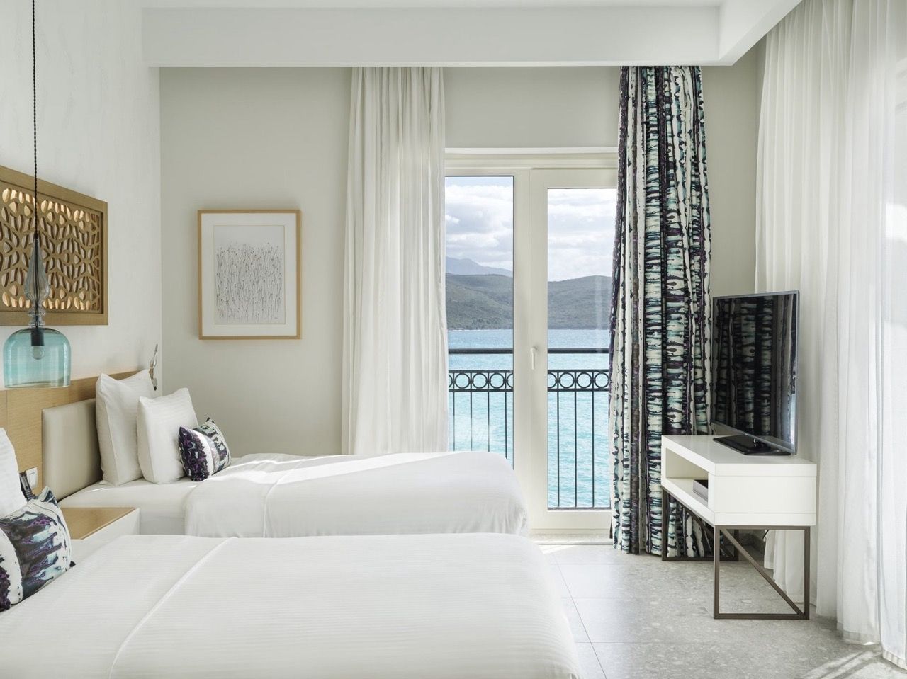 Bedroom in Lustica Bay apartments, Radovici, Montenegro: two beds, modern furniture, and sea view from the balcony.