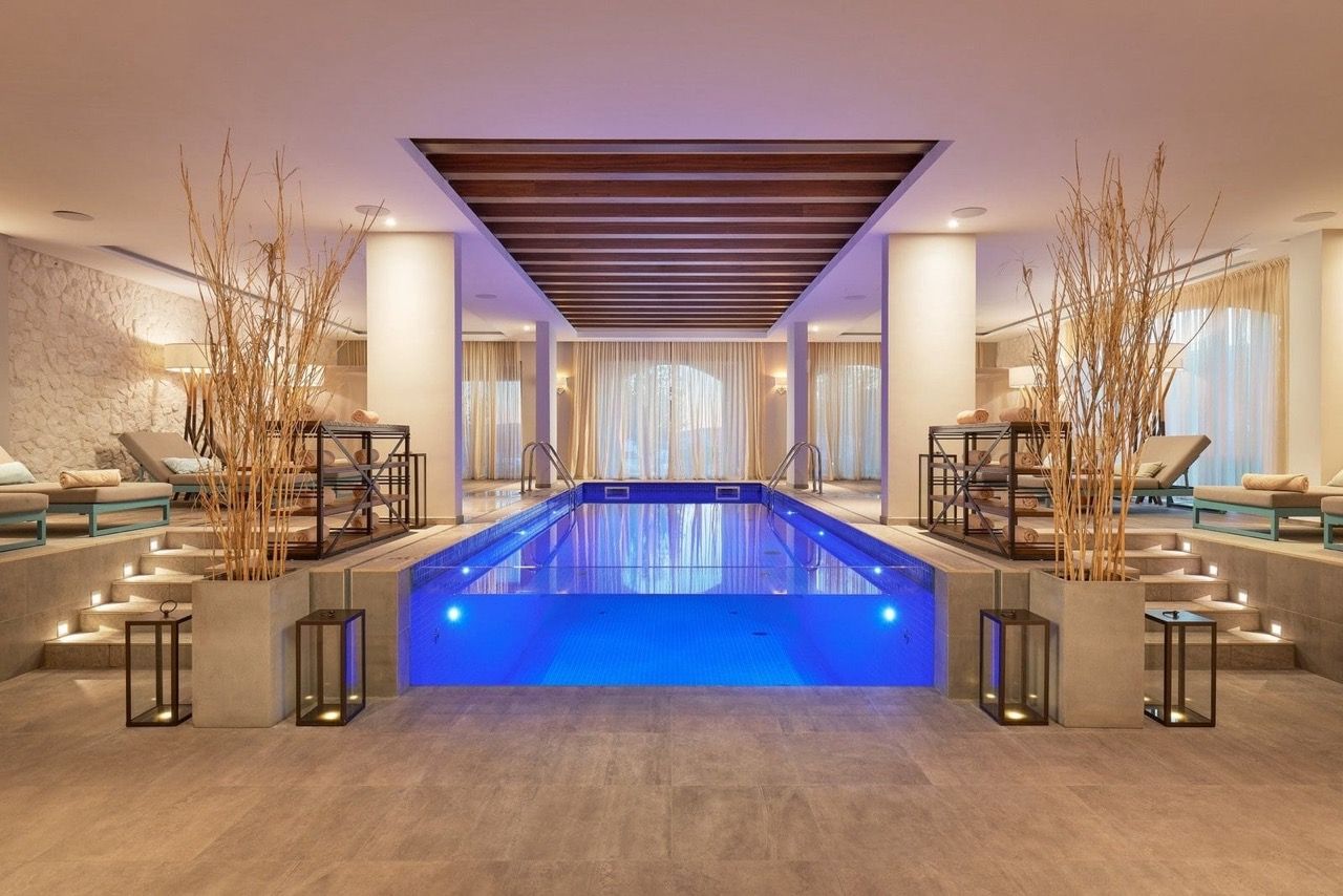Indoor illuminated pool in the spa center of the Lustica Bay complex, Radovici, Montenegro: sun loungers and stylish interior.
