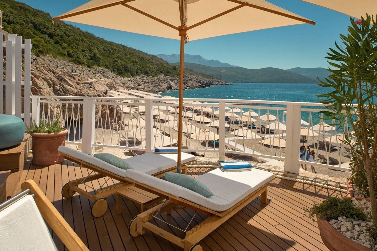Terrace with sun loungers and a view of the beach in Luštica Bay, Radovići, Montenegro: wooden deck and sea view.