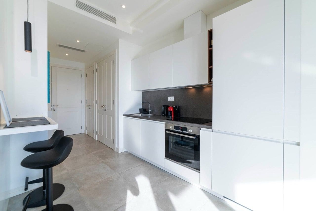 Modern white kitchen in an apartment in Lustica Bay, Radovici, Montenegro: built-in appliances and a breakfast bar.