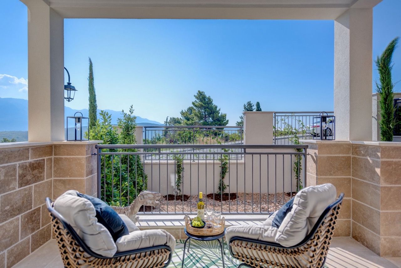 Cozy terrace with wicker chairs and mountain views in an apartment in Luštica Bay, Radovići, Montenegro.