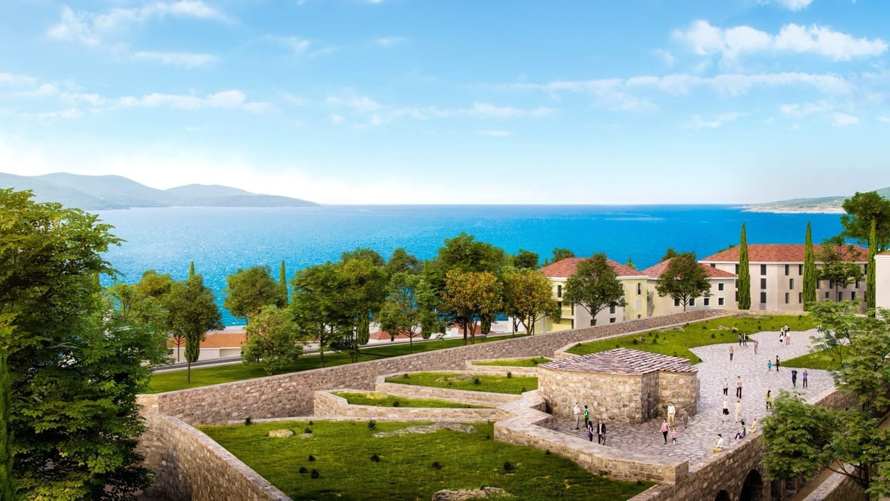 View of the Lustica Bay residential complex in Radovici, Montenegro: stone architecture, manicured lawns, and a sea view.