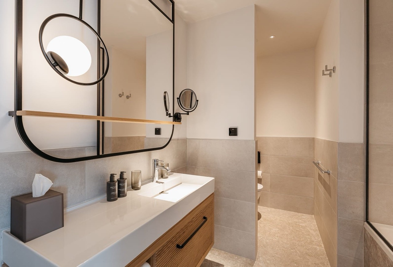 Modern bathroom in an apartment in Porto Montenegro, Tivat, Montenegro: stylish vanity, mirror, and light-colored tiles.
